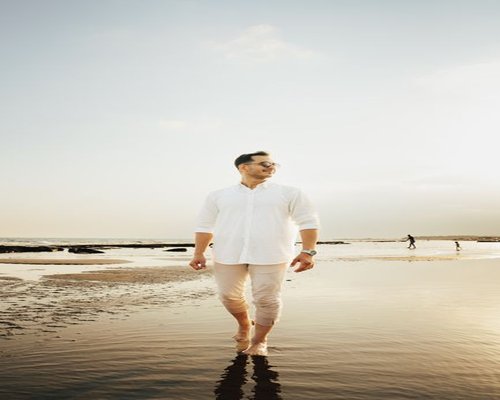 A balanced healthy male professional enjoying a peaceful evening walk along the coastline of East Coast Park Singapore representing daily vitality