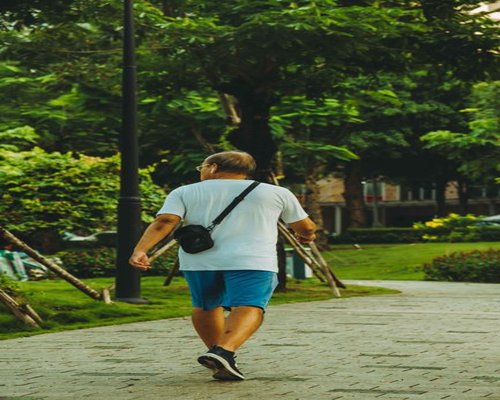 A professional man wearing lifestyle athletic apparel exercising or enjoying a fast evening walk along a lush green pathway in Singapore